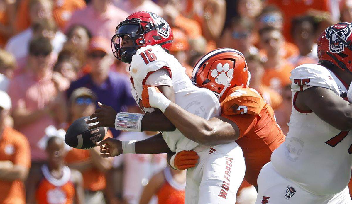 N.C. State quarterback Grayson McCall (2) loses the ball while being sacked by Clemson defensive end T.J. Parker (3) during the first half of N.C. State’s game against Clemson at Memorial Stadium in Clemson, S.C., Saturday, Sept. 21, 2024.