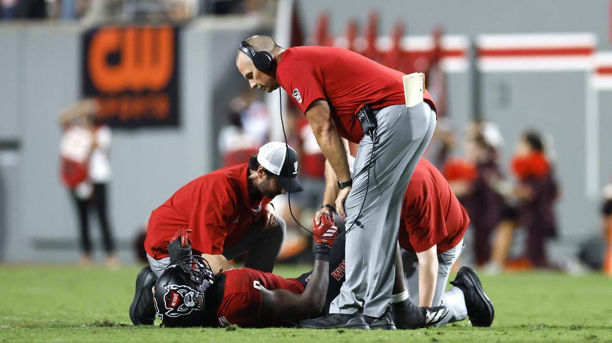 N.C. State head coach Dave Doeren holds onto the hand of linebacker Sean Brown (0) after he was injured in the second half of Virginia Tech’s 23-21 victory over N.C. State at Carter-Finley Stadium in Raleigh, N.C., Saturday, Sept. 27, 2025.