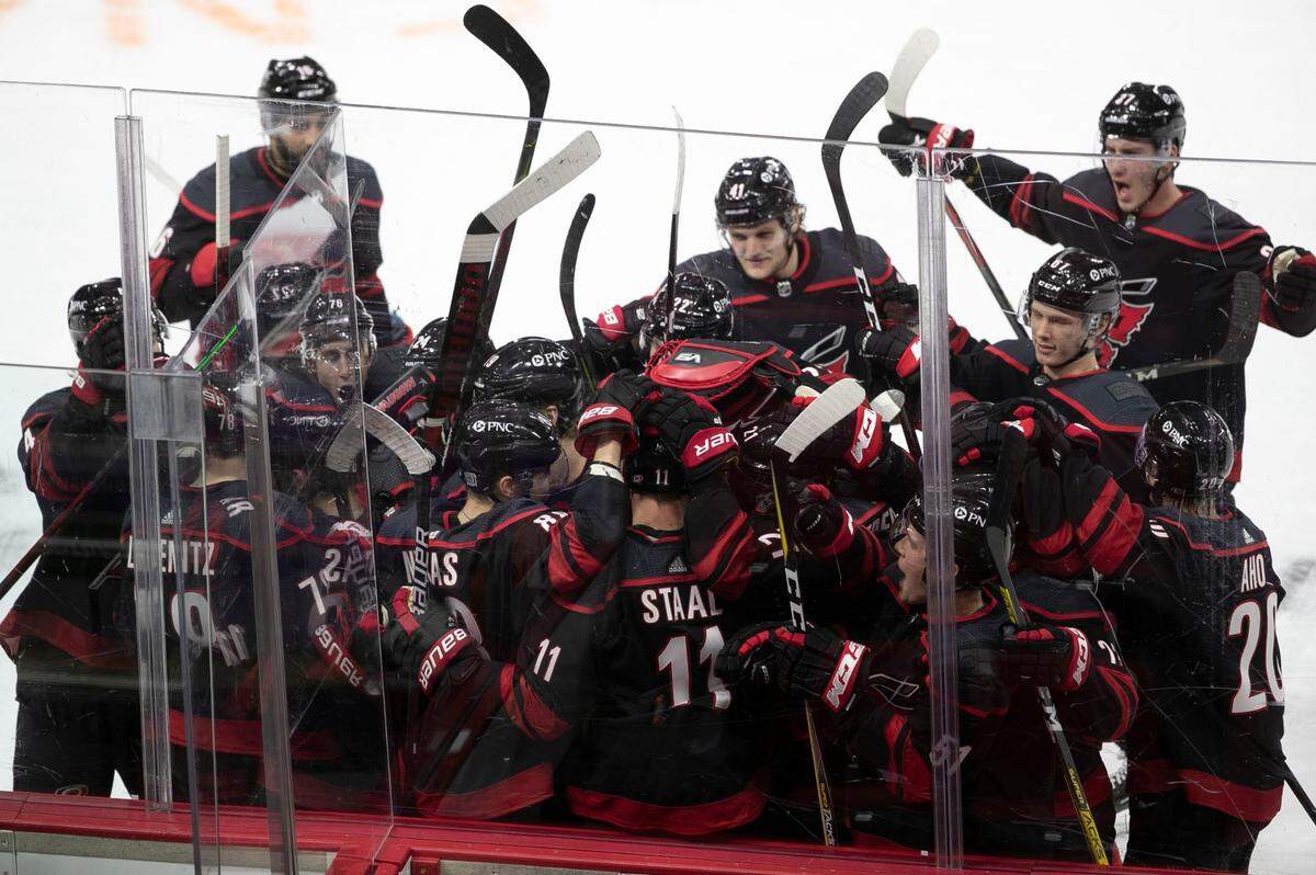Carolina Hurricanes Martin Necas (88) embraces teammate Jordan Staal (11) who had an assist on the game winning goal as they celebrate their 1-0 overtime victory with teammates in their season home opener on Thursday, January 28, 2021 at PNC Arena in Raleigh, N.C.
