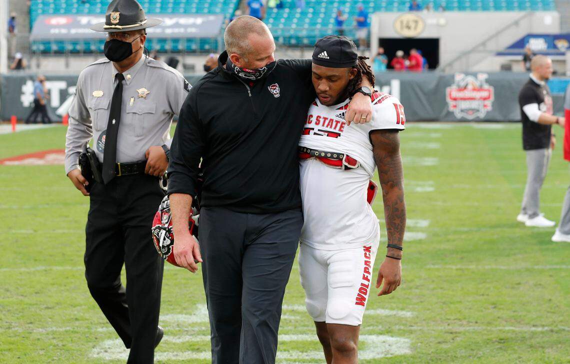 N.C. State head coach Dave Doeren talks with Keyon Lesane (15) as they walk off the field after Kentucky’s 23-21 victory over N.C. State in the Gator Bowl at TIAA Bank Field in Jacksonville, Fla., Saturday, January 2, 2021.
