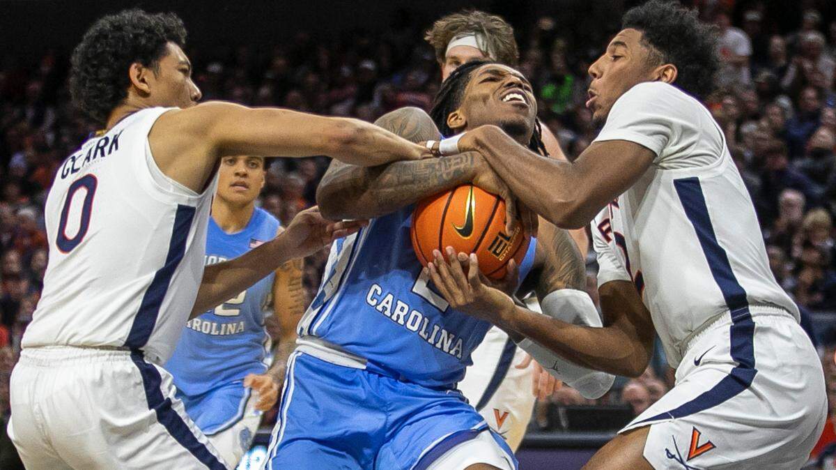 Virginia’s Kihei Clark (0) and Reece Beekman (2) stop North Carolina’s Caleb Love (2) as he drives to the basket in the second half on Tuesday, January 10, 2023 at John Paul Jones Arena in Charlottesville, Va. Virginia defeated North Carolina 65-58.