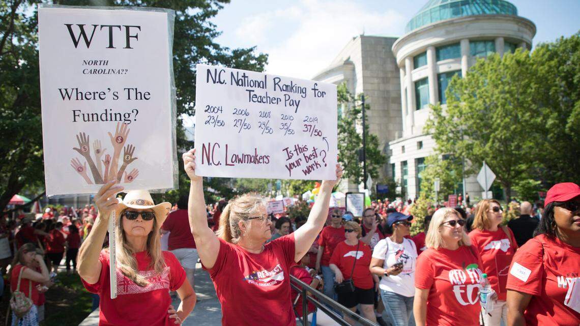 Educators and supporters hold signs outside the legislative building in downtown Raleigh before a rally on Wednesday, May 1, 2019.