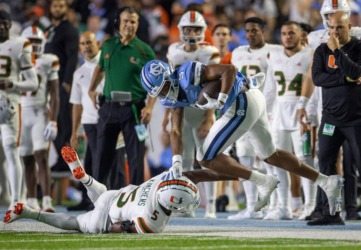 North Carolina’s J.J. Jones (5) picks up 48 yards on a pass completion from quarterback Drake Maye before being stopped by Miami’s Kamren Kinchens (5) in the first quarter on Saturday, October 14, 2023 at Kenan Stadium in Chapel Hill, N.C.