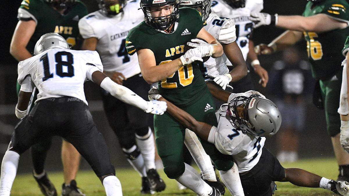 Apex running back Kaiden Dupree (20) runs for yardage against Panther Creek’s Michael Fogg (18) and Amir Spencer (7) during the second half. The Apex Cougars and the Panther Creek Catamounts met in a conference football game in Apex, N.C. on September 20, 2024.