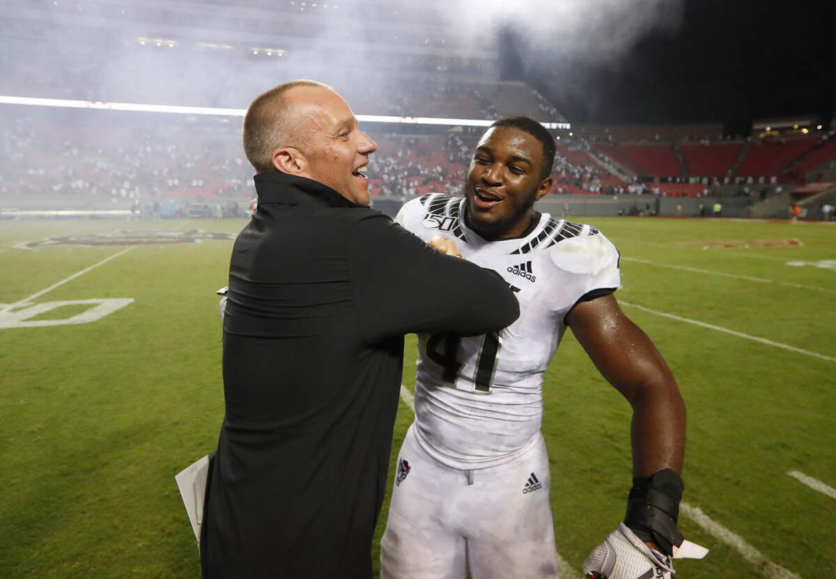 N.C. State head coach Dave Doeren celebrates with Isaiah Moore (41) after N.C. State’s 16-10 victory over Syracuse at Carter-Finley Stadium in Raleigh, N.C., Thursday, Oct. 10, 2019.