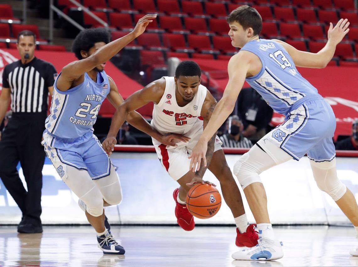 N.C. State’s Thomas Allen (5) drives by North Carolina’s Kerwin Walton (24) and Walker Kessler (13) during the first half of N.C. State’s game against UNC at PNC Arena in Raleigh, N.C., Tuesday, December 22, 2020.