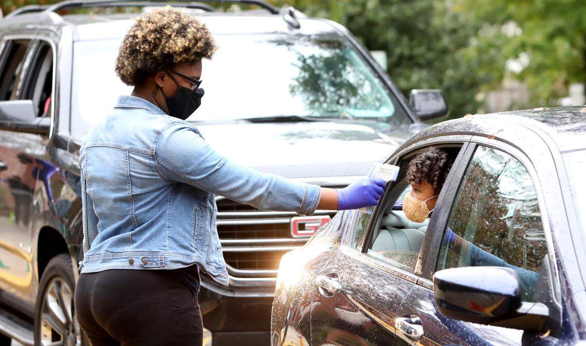 Hunter Elementary School teachers conduct health screenings at cars during drop-off in Raleigh on Monday, October 26, 2020, on the first day back in school for some Wake students.