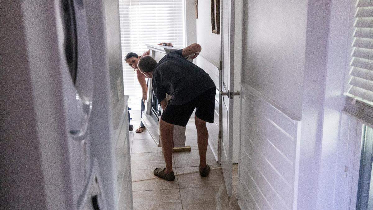 Chase Hobson helps his neighbor Shanda Rickert move furniture from Ricket’s flooded ground-level apartment in Kure Beach on Tuesday, Sept. 17, 2024 after an unnamed storm dropped as much as 18 inches of rain in southeastern North Carolina over a 72-hour period.