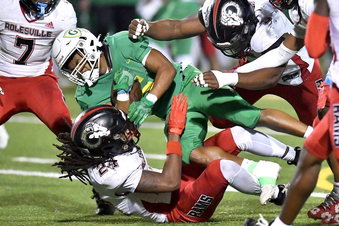 Rolesville’s Xavier Lewis (3) and Jayden Griffin-Haynes (5) tackle Cardinal Gibbons wide receiver Kendall Scotton (5) during the first half. The Rolesville Rams and the Cardinal Gibbons Crusaders met in the East Regional Final of the NCHSAA 4A football playoffs in Raleigh, N.C. on December 13, 2024.