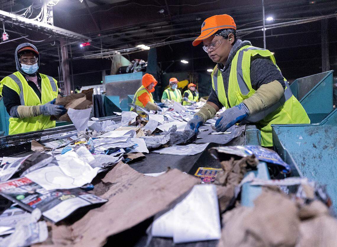 Martina Garcia, right, works on the paper quality control line at a Sonoco materials recovery facility on Tuesday, Jan. 17, 2023, in Raleigh, N.C. The recycling plant receives material from all of Raleigh’s residential blue bins, along with recycling from Durham, Fuquay-Varina and some smaller community drop-off centers.