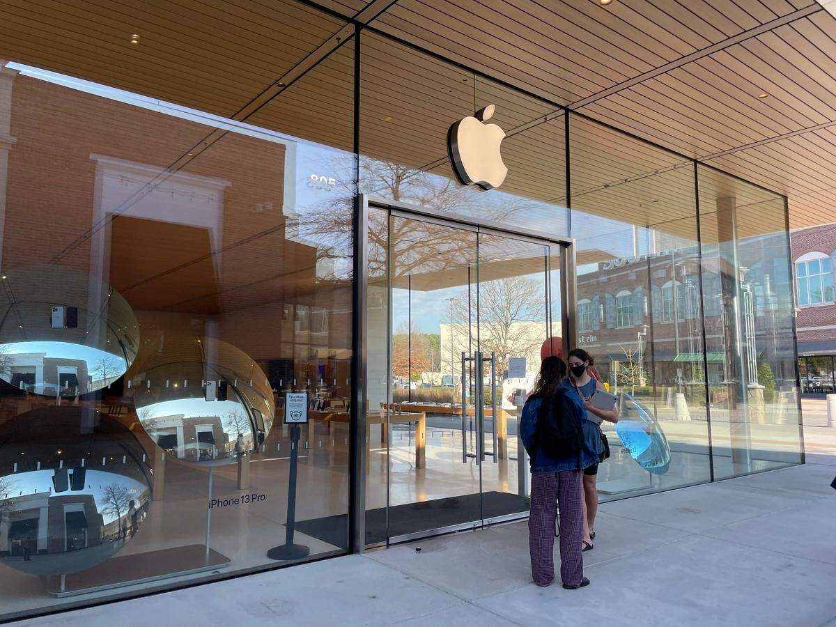 Two would-be customers wait outside of closed Apple store in Durham, N.C., on Dec. 28, 2021.