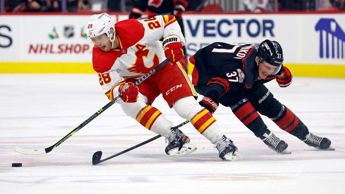 Calgary Flames’ Elias Lindholm (28) skates the puck around Carolina Hurricanes’ Andrei Svechnikov (37) during the second period of an NHL hockey game in Raleigh, N.C., Saturday, Nov. 26, 2022. (AP Photo/Karl B DeBlaker)