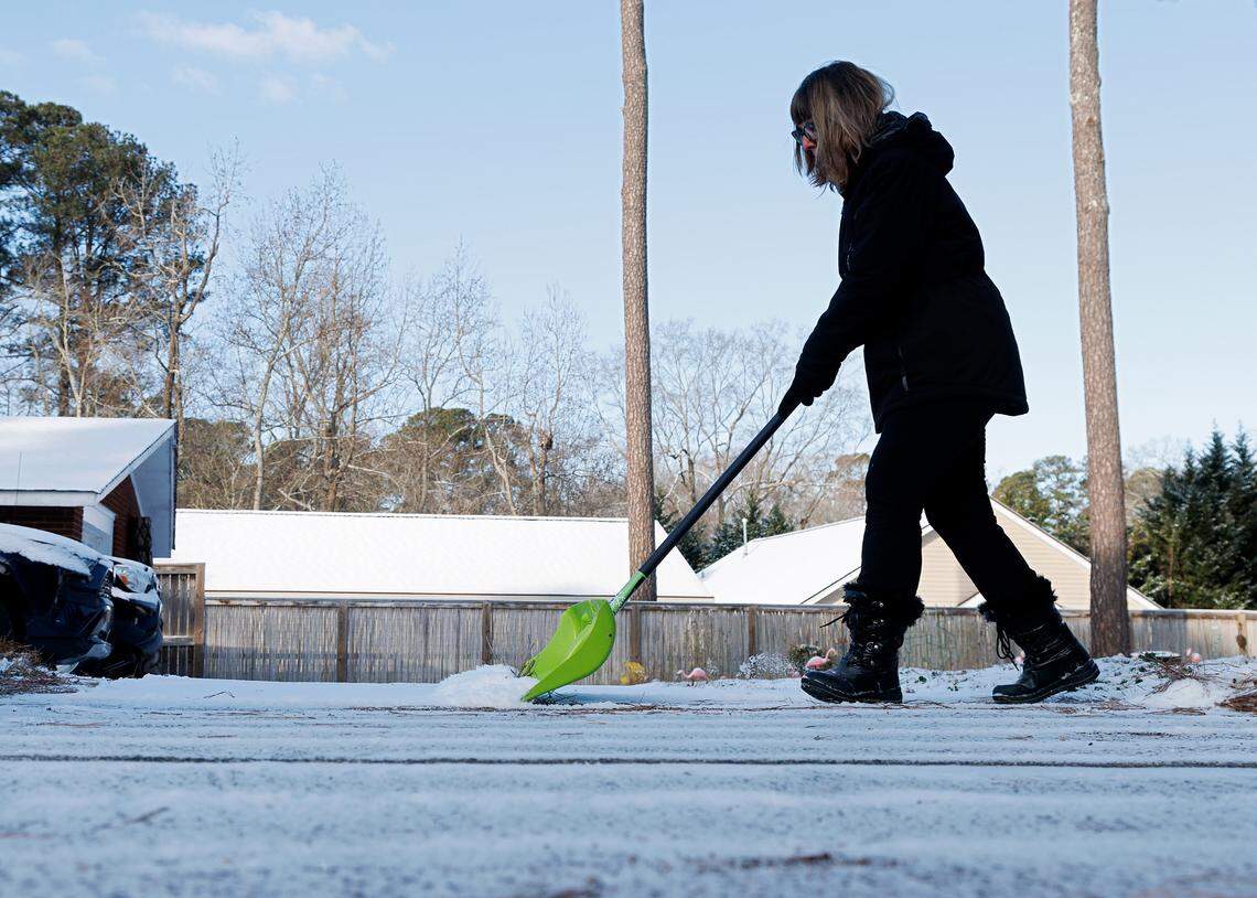 Margo Scott works to clear snow and ice from a driveway in Durham, N.C. on Wednesday, Jan. 22, 2025.