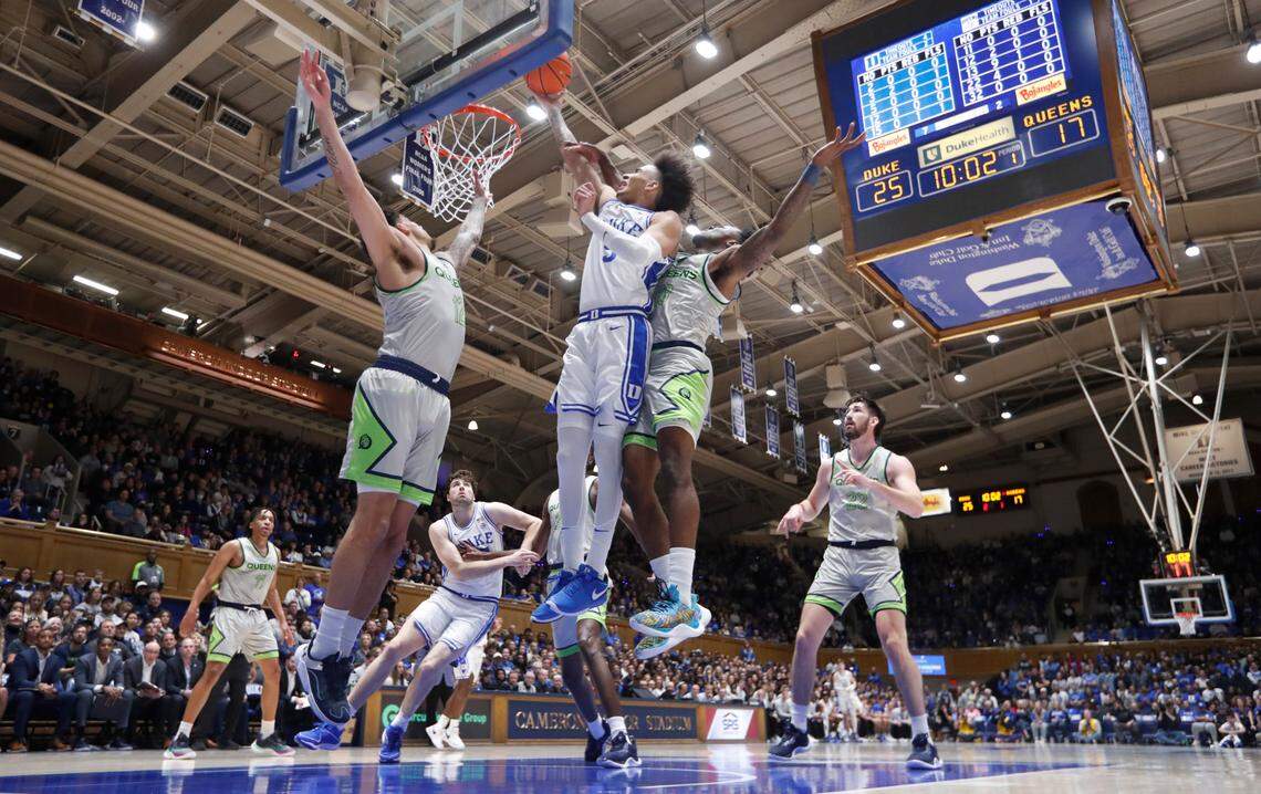 Duke’s Tyrese Proctor (5) shoots while defended by Queens’ Logan Threatt (12), left, and Deyton Albury (13) during Duke’s 106-69 victory over Queens University at Cameron Indoor Stadium in Durham, N.C., Saturday, Dec. 30, 2023.