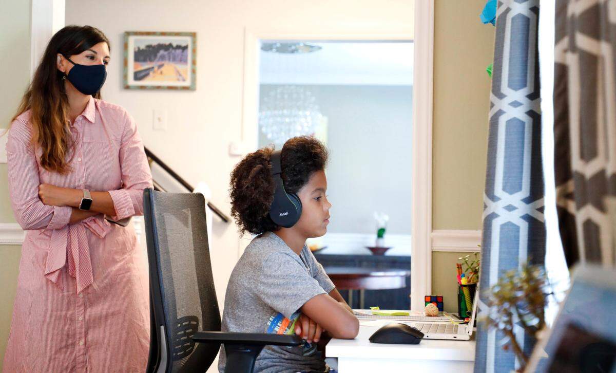 As his mother Juliette takes a peak, Harper Grimmett attends his day of classes as a sixth grader at Ligon Middle School while at their home in Raleigh, N.C. Monday, August 17, 2020. They enrolled in the Wake County Virtual Academy in the 2020-21 school year.