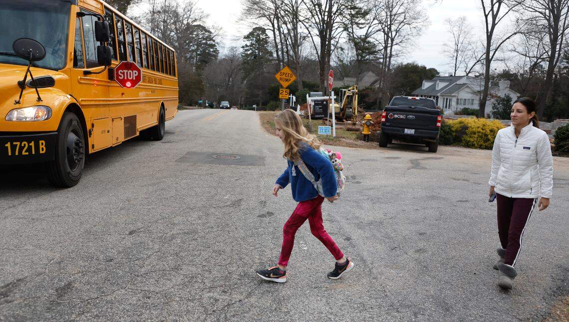 Ilsy Chappell watches as he daughter Sienna cross the street to board the school bus for Hunter Elementary School in Raleigh, N.C., Tuesday, Jan. 17, 2023.