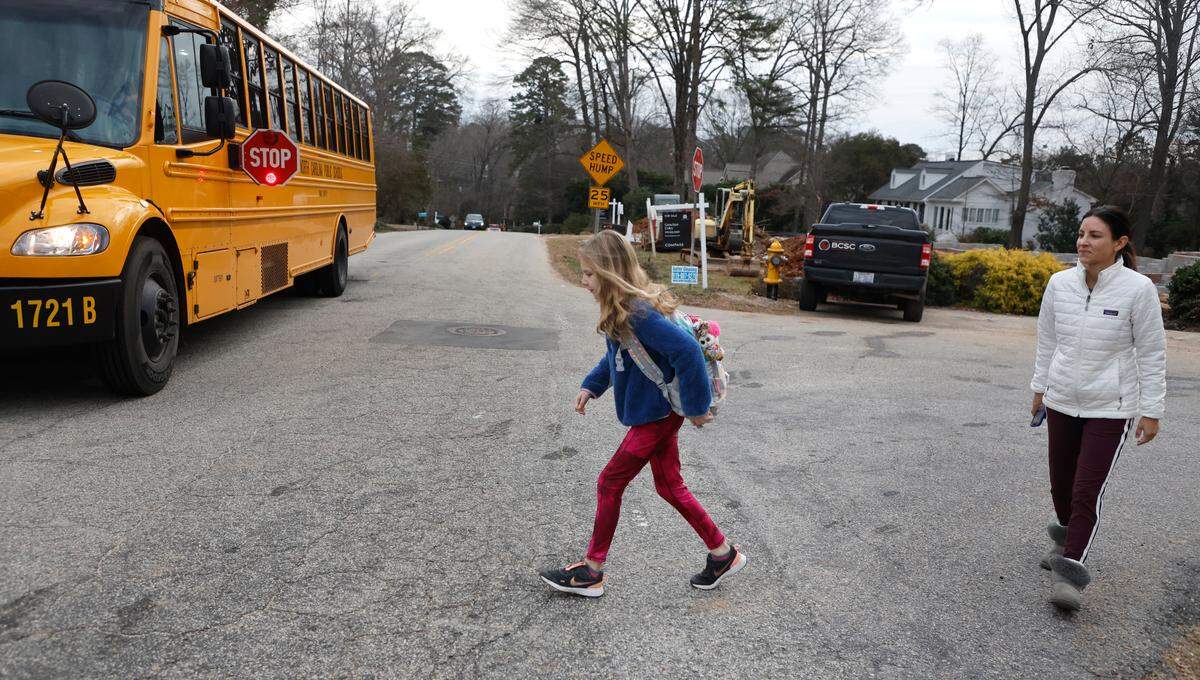 Ilsy Chappell watches as he daughter Sienna cross the street to board the school bus for Hunter Elementary School in Raleigh, N.C., Tuesday, Jan. 17, 2023. School districts across the nation are experiencing a bus driver shortage.