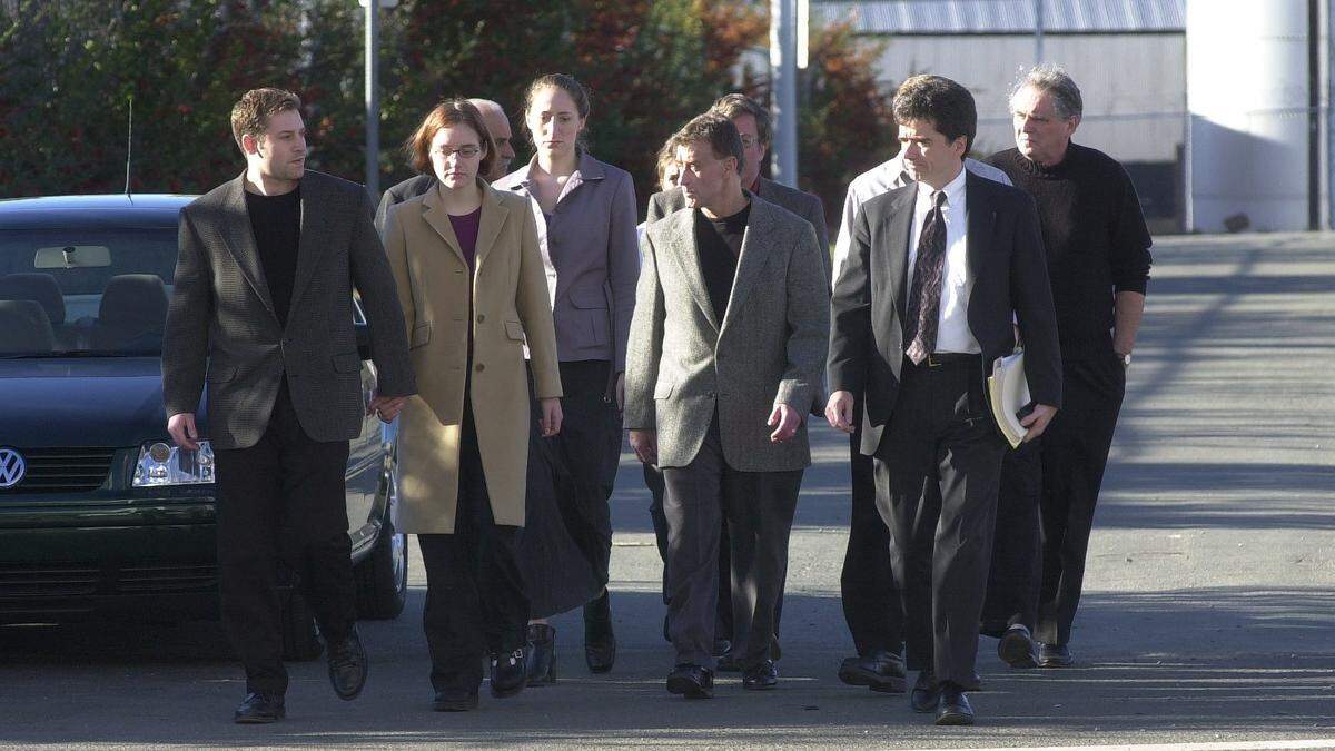 Michael Peterson (center in black shirt) walks with family, supporters, and attorney as he arrives to turn himself in after being indicted for the murder of his wife Kathleen, Dec. 20, 2021.