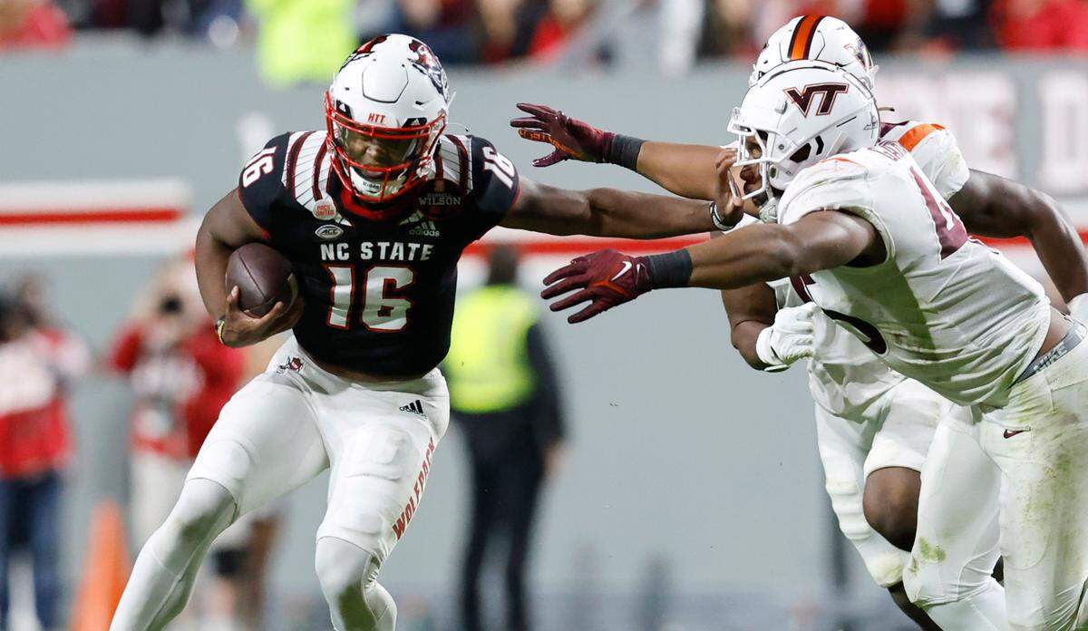 N.C. State quarterback MJ Morris (16) tries to stiff-arm Virginia Tech defensive lineman TyJuan Garbutt (45) during the first half of N.C. State’s game against Virginia Tech at Carter-Finley Stadium in Raleigh, N.C., Thursday, Oct. 27, 2022.