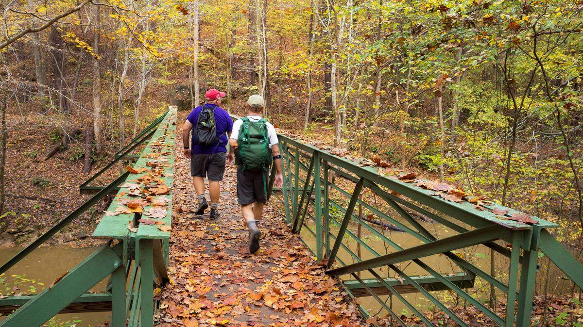 Hikers cross a bridge in William B. Umstead State Park, named by Yelp users as one of the top 20 places in the U.S. to go to see the changing colors of fall.