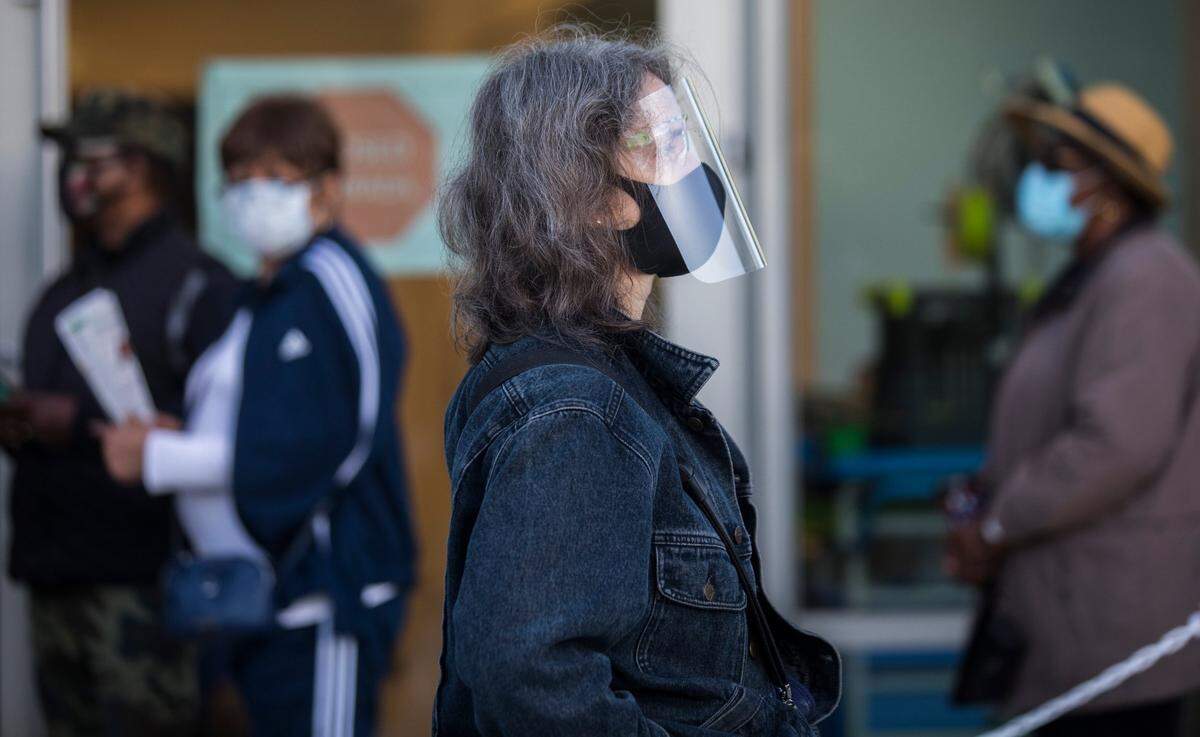 Jaimie Graff wears a face shield as she waits in line outside the Durham County Main Library in Durham, N.C. to vote on the morning of the first day of early voting, Thursday, Oct. 15, 2020.