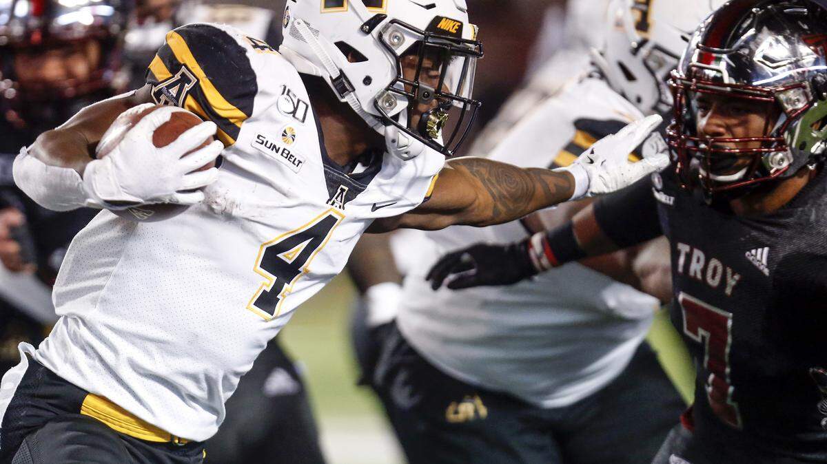 Appalachian State running back Daetrich Harrington (4) stiff-arms Troy linebacker KJ Robertson (7) during the second half of an NCAA college football game Friday, Nov. 29, 2019, in Troy, Ala. (AP Photo/Butch Dill)