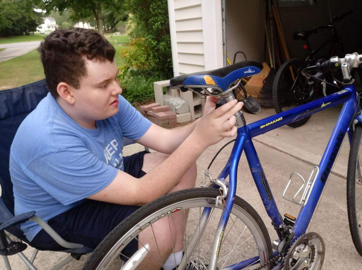 Ben Holland attaches a light to the back of his dad Jeff’s bicycle in late summer, 2019. Ben is diagnosed with Autism, and will be moving into his own house soon. 