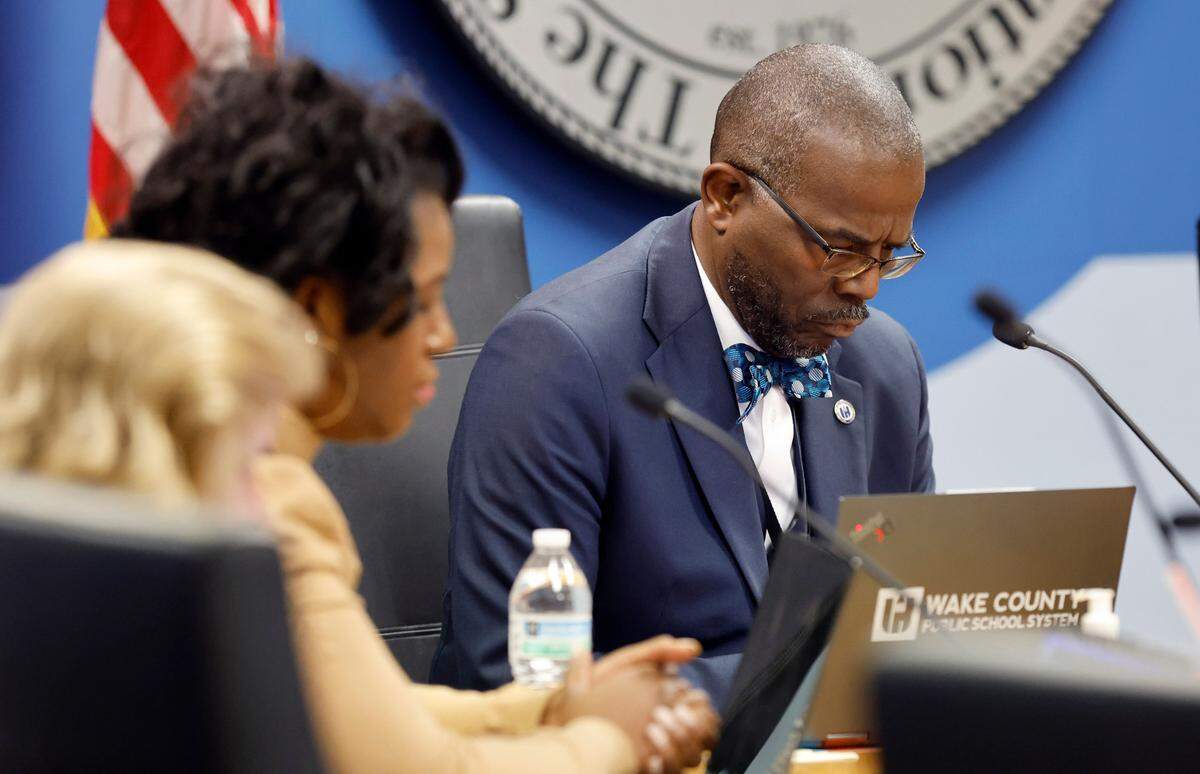 Wake County School Superintendent Robert Taylor and board members including Tara Waters, left, bow their head during a moment of silence at the start of the Wake County School Board Safety and Security meeting in Cary, N.C., Tuesday, Nov. 28, 2023. The board was going to discuss in closed session the deadly fight at Southeast Raleigh High School Monday.