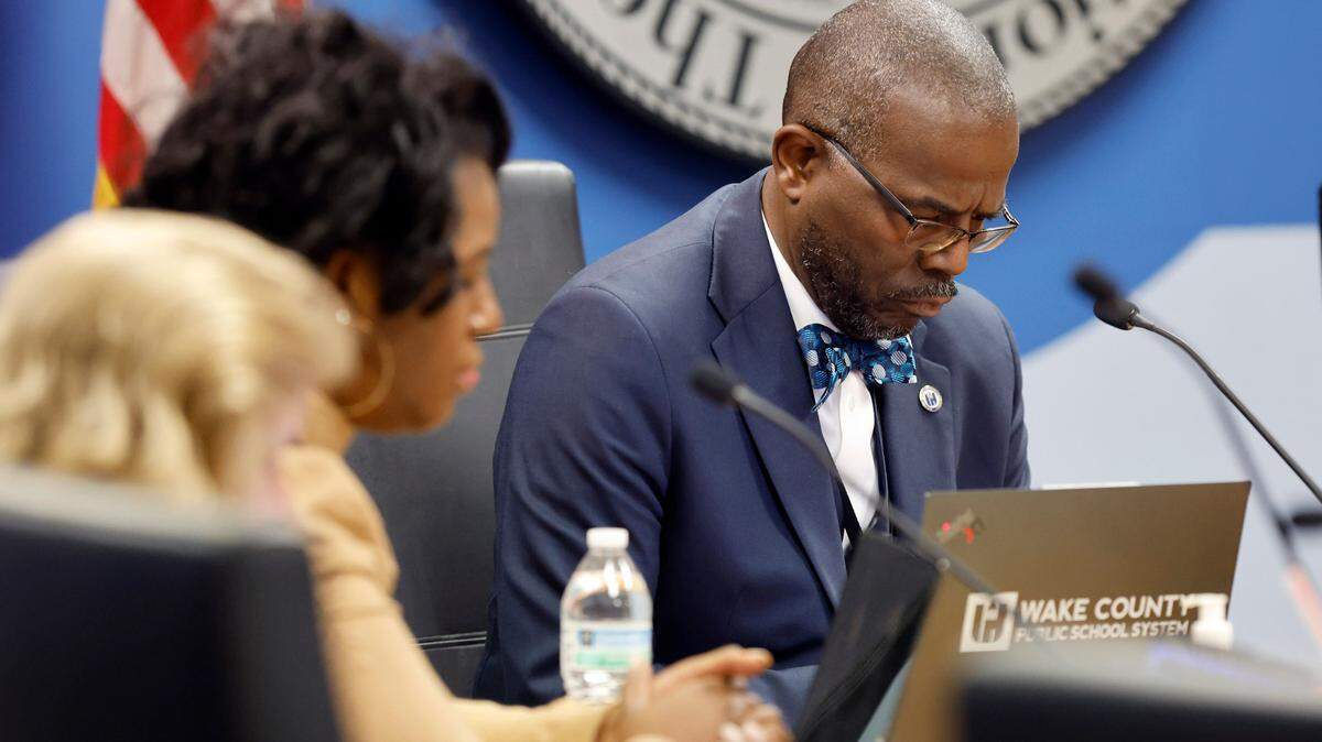 Wake County School Superintendent Robert Taylor and board members including Tara Waters, left, bow their head during a moment of silence at the start of the Wake County School Board Safety and Security meeting in Cary, N.C., Tuesday, Nov. 28, 2023. The board was going to discuss in closed session the deadly fight at Southeast Raleigh High School Monday.