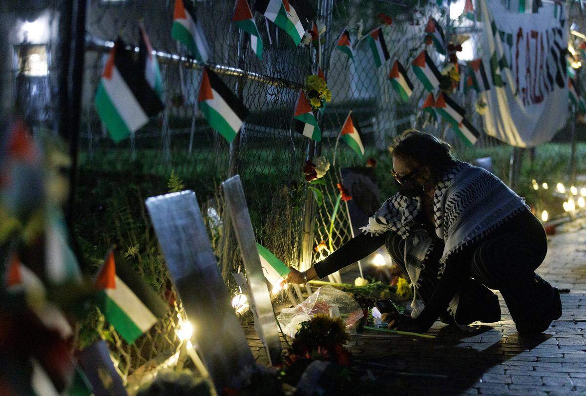 A person pauses at the foot of a memorial near the Old Well at the conclusion of a vigil held by the UNC chapter of Students for Justice in Palestine on Monday, Oct. 7, 2024, in Chapel Hill, N.C. The vigil was intended to honor those who have been killed during Israel’s counter-campaign against Hamas in the past year.