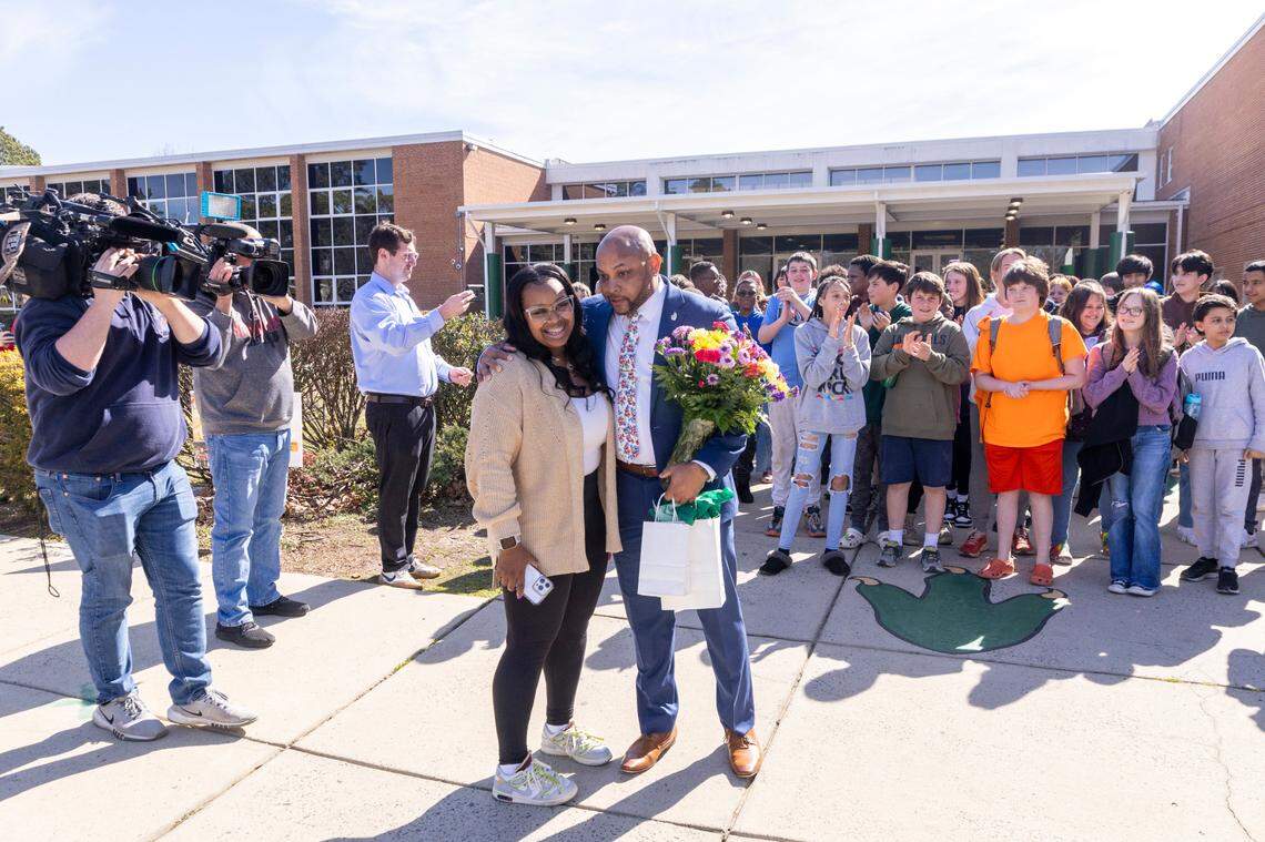 Brogden Middle School Principal Anthony White presents bus driver Deona Washington with a bouquet of flowers during a hero’s welcome on Monday, Feb. 20, 2024, at the Durham school. Washington safely evacuated all 28 of her students from a school bus engulfed in flames on Friday.