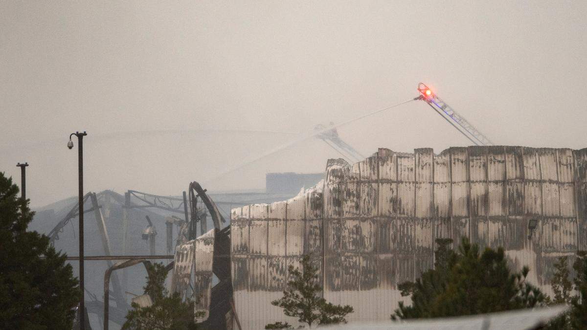 Aerial water cannons continue to spray water on sections of the QVC shipping facility in Rocky Mount, N.C. Sunday morning, Dec. 19. 2021 after a fire that started early Saturday morning gutted large sections of the building, collapsing the roof and parts of some walls.