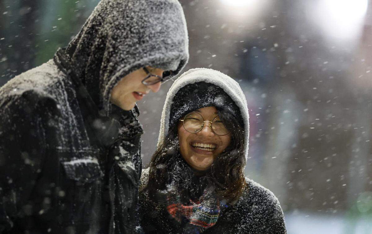 Muhua Liu and Paul Jaskowski enjoy the snow in the Glenwood South district in Raleigh, N.C., Saturday evening, Jan. 31, 2026.