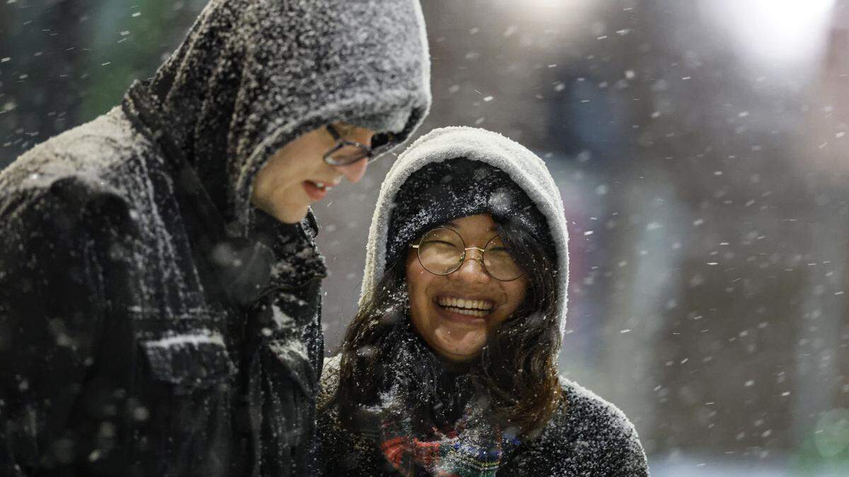 Muhua Liu and Paul Jaskowski enjoy the snow in the Glenwood South district Saturday evening. Extremely cold temperatures followed the snow, and Duke Energy took steps to reduce the chance of power blackouts in the state. 
