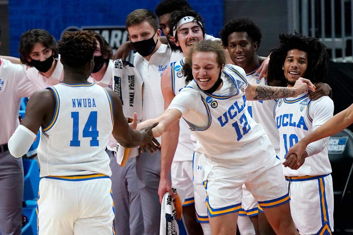 UCLA’s Mac Etienne (12) slaps hands with Kenneth Nwuba (14) in the final moments of their 67-47 win over Abilene Christian in a college basketball game in the second round of the NCAA tournament at Bankers Life Fieldhouse in Indianapolis Monday, March 22, 2021. 