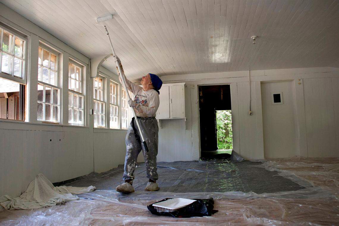 Jean Spooner, chairwoman of the Umstead Coalition, paints the ceiling of the kitchen in the Sycamore Camp mess hall on May 27, 2015, at Umstead State Park in Raleigh. The Sycamore Camp was completed in 1934 by the Works Progress Administration.