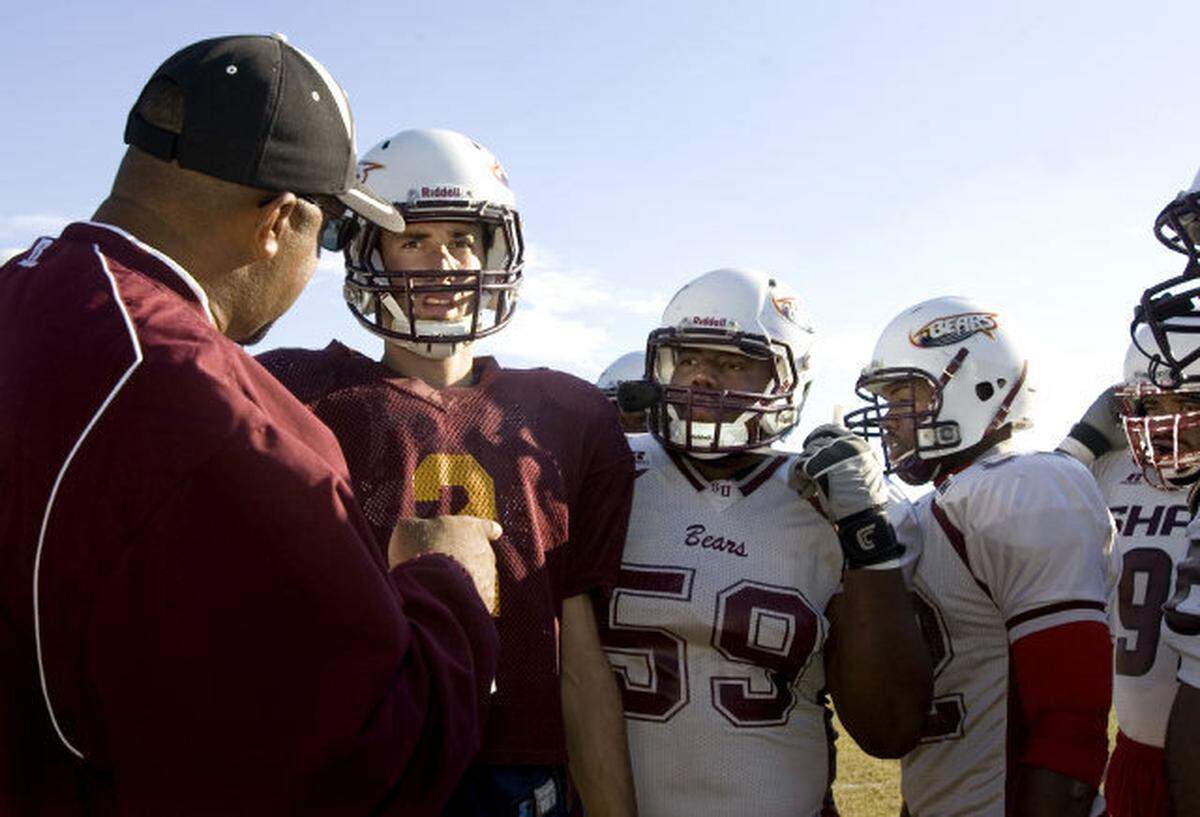Shaw University Assistant Head Coach, Offensive Coordinator and Quarterback Coach Maurice Flowers, left, works with James Stallons, center, and other team members during their practice at Chavis Park in Raleigh on Wednesday, October 17, 2012.