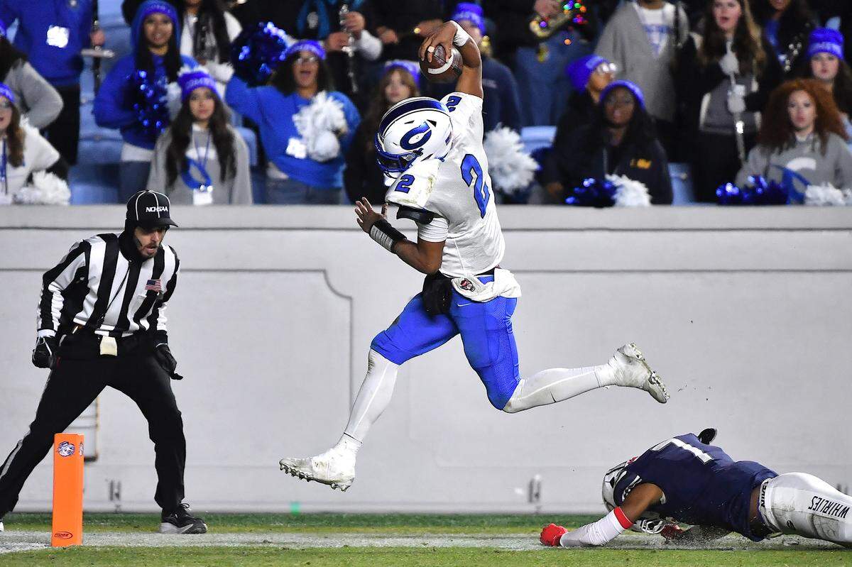 Clayton quarterback Aiden Smalls (2) leaps past Grimsley corner back Patrick Carter (7) for the touchdown during the second half.   The Clayton Comets and the Grimsley Whirlies met in the NCHSAA 7A football Championships in Chapel Hill, NC on December 12, 2025.