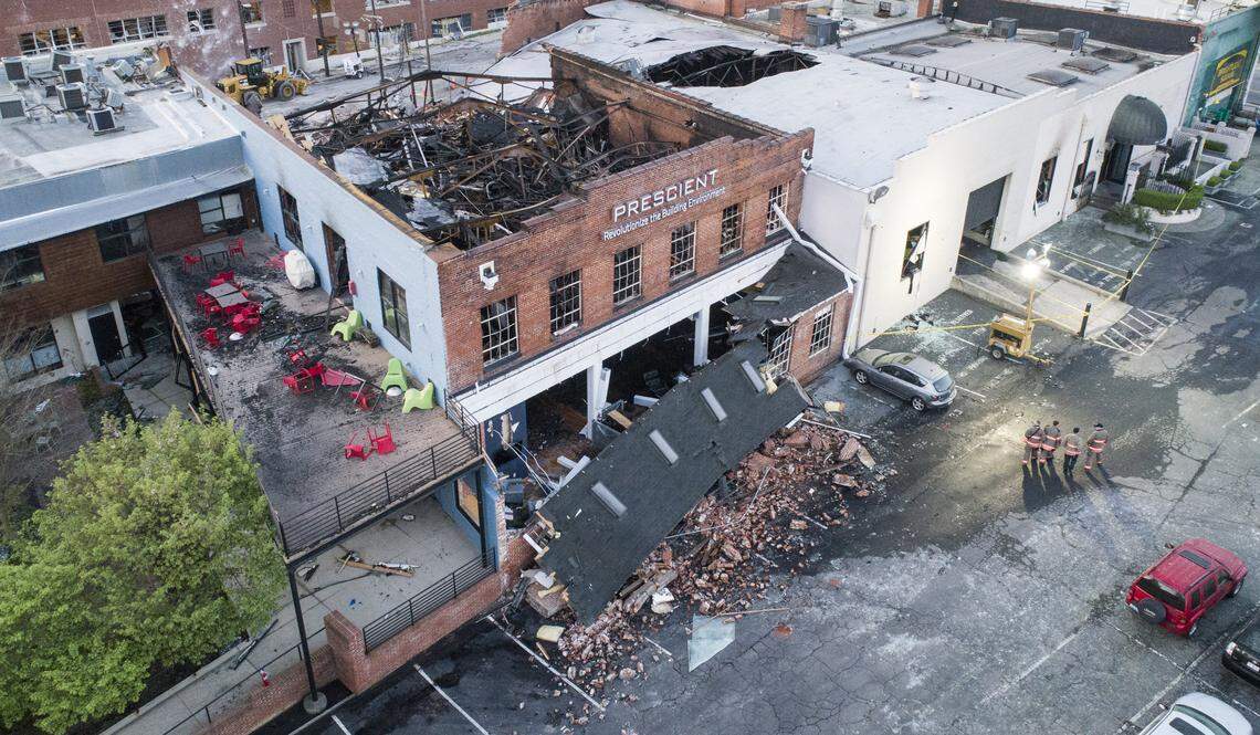 Firefighters walk through the parking lot of the collapsed building near Brightleaf Square in Durham on Thursday, April 11, 2019. The collapse occurred after a gas leak lead to an explosion on Wednesday.