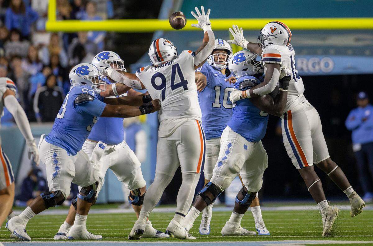 North Carolina offensive lineman Willie Lampkin (53) works to protect quarterback Drake Maye from Virginia’s Aaron Faumui (94), as he and Michael Diatta (18) pressure Maye during the second quarter on Saturday, October 21, 2023 at Kenan Stadium in Chapel Hill, N.C.