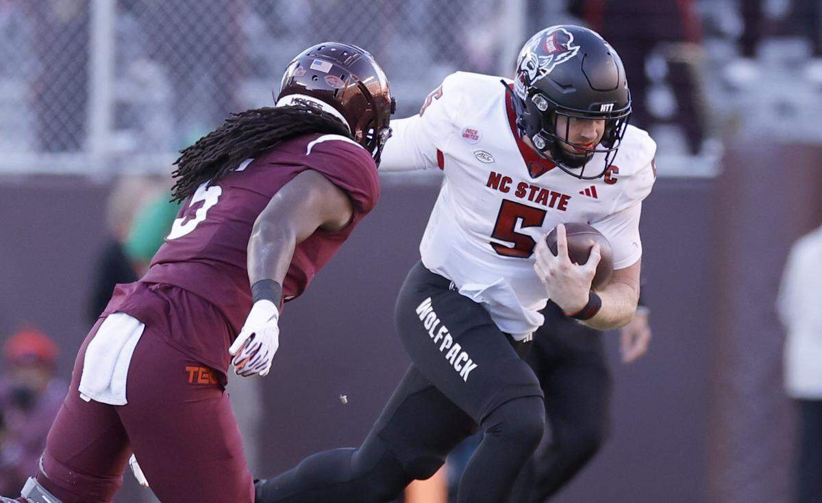 N.C. State quarterback Brennan Armstrong (5) looks to run past Virginia Tech safety Nasir Peoples (5) during the first half of N.C. State’s game against Virginia Tech at Lane Stadium in Blacksburg, VA, Saturday, Nov. 18, 2023.