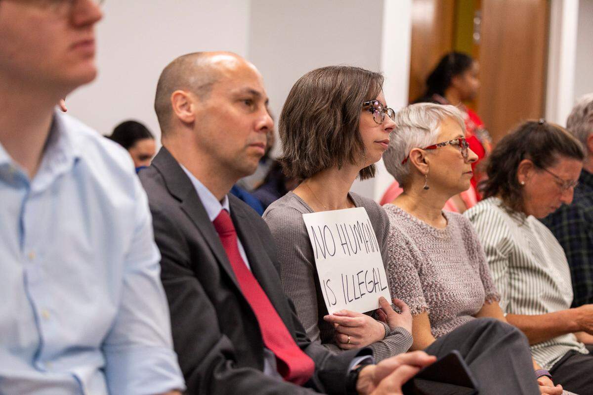 A woman holds a sign that reads, “No human is illegal,” during a Senate Judiciary Committee meeting at the Legislative Office Building, where a Senate Republican immigration bill was heard.