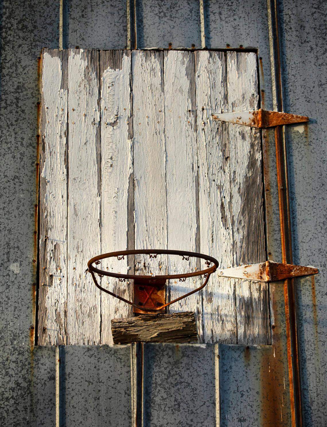A rusting basketball hoop without a net and a makeshift backboard are attached to the side of an old tobacco barn in rural North Carolina.