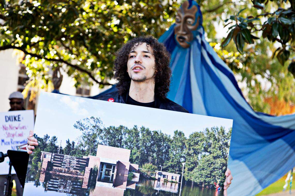 Lumbee member Jordan Revels holds up a photo of the Robeson Planetarium damaged by flooding as he speaks outside the Governor’s Mansion in Raleigh on Friday, Nov. 19, 2021, during a protest about the climate emergency. Seventeen groups around the state gathered to protest Duke Energy’s plans to build 50 gas-burning power units.
