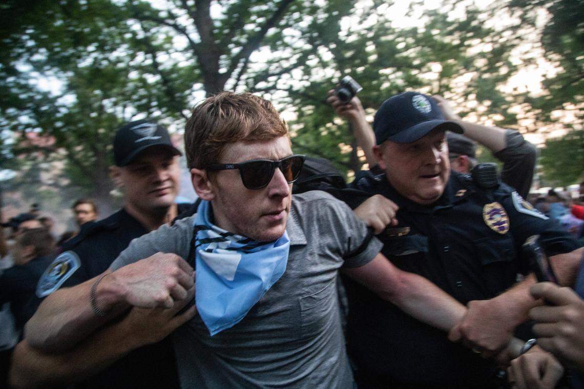 A protestor is led away by police as demonstrators cover Silent Sam with banners Monday, Aug. 20, 2018, at UNC-Chapel Hill.