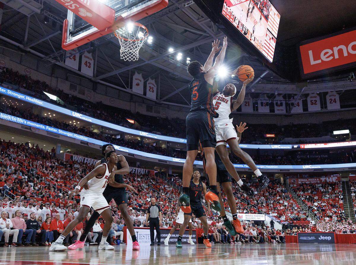 N.C. State’s Tre Holloman drives to the basket against Miami’s Malik Reneau during the second half of the Wolfpack’s 77-76 loss on Saturday, Feb. 14, 2026, at Lenovo Center in Raleigh, N.C.