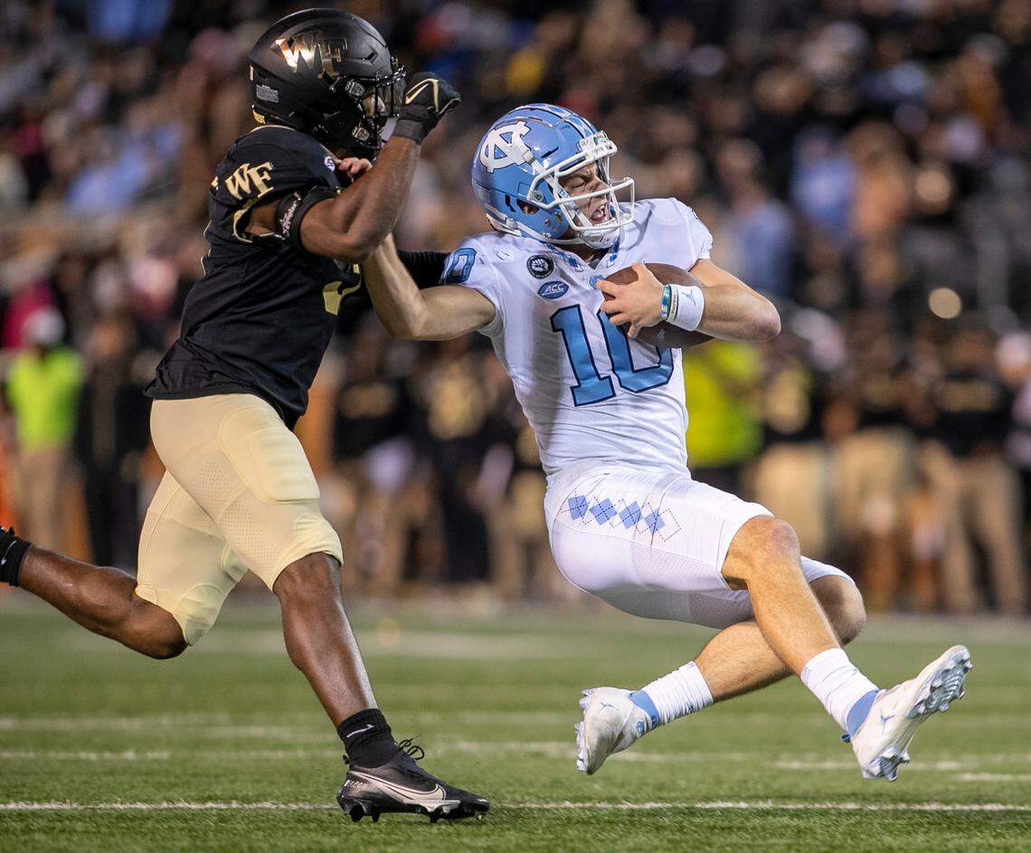 North Carolina quarterback Drake Maye (10) slides to the turf after a ten-yard gain the third quarter as Wake Forest’s Chelen Garnes (9) and J.J,Roberts (12) approach to stop him on Saturday, November 12, 2022 at Truist Field in Winston-Salem, N.C.