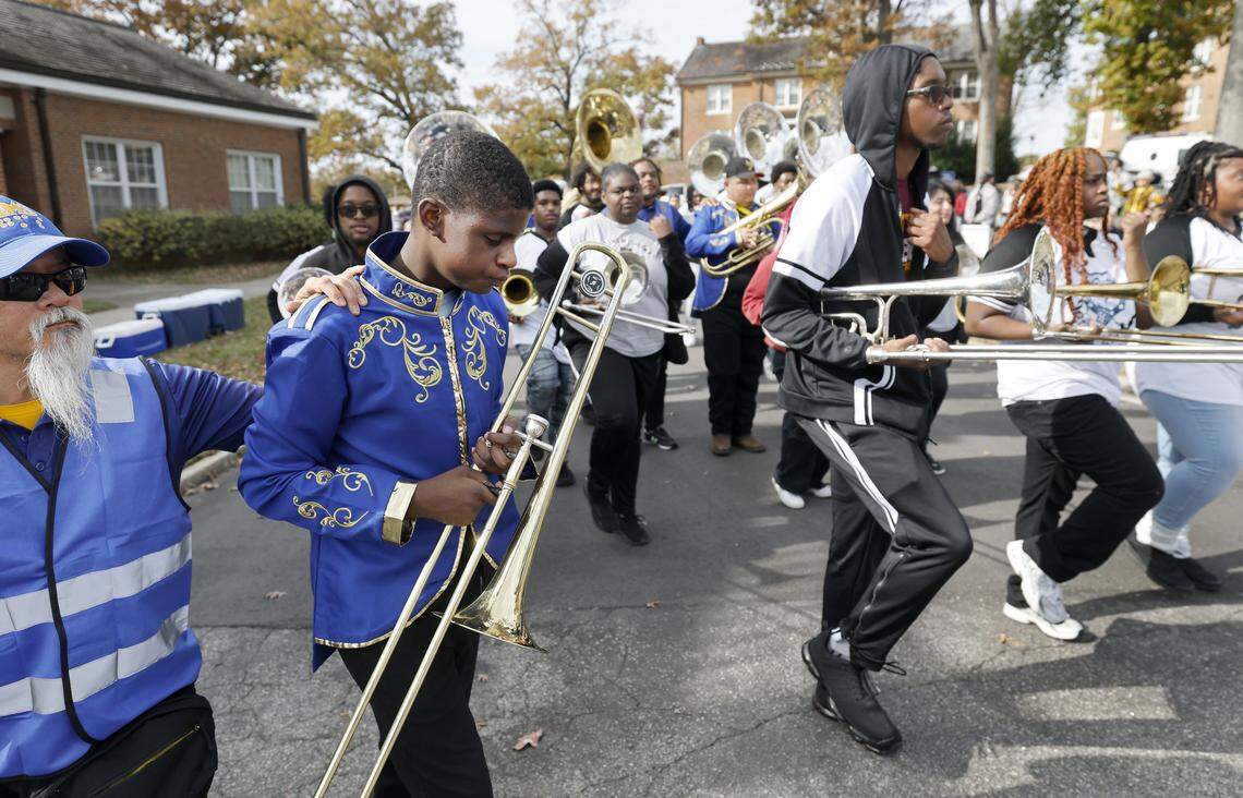 Tyquan Smart, left, a member of the Governor Morehead School for the Blind’s marching band, performs with the marching bands of Shaw University and Southeast Raleigh High School in the school’s homecoming parade in Raleigh on Thursday. The parade is part of the schooll’s 180th anniversary celebration  William Tubilleja, orientation and mobility instructor, helps Smart.