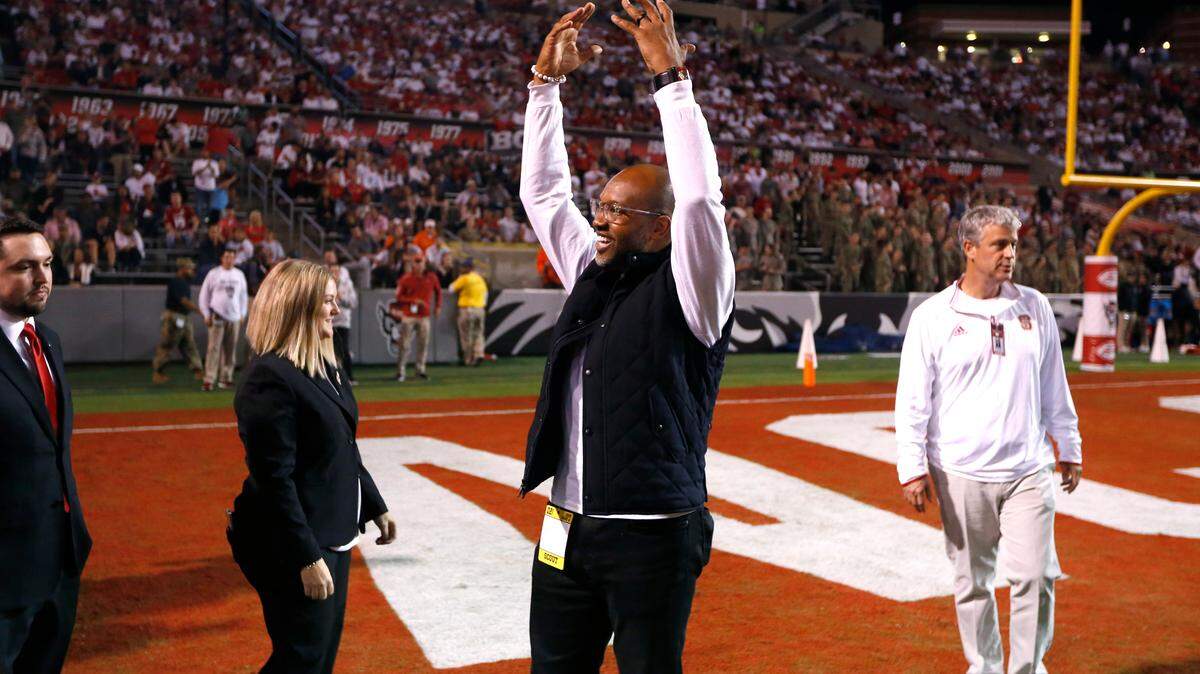 Former N.C. State receiver Torry Holt acknowledges the crowd during a ceremony honoring Holt’s induction into the College Football Hall of Fame during the first half of N.C. State’s game against Syracuse at Carter-Finley Stadium in Raleigh, N.C., Thursday, Oct. 10, 2019.
