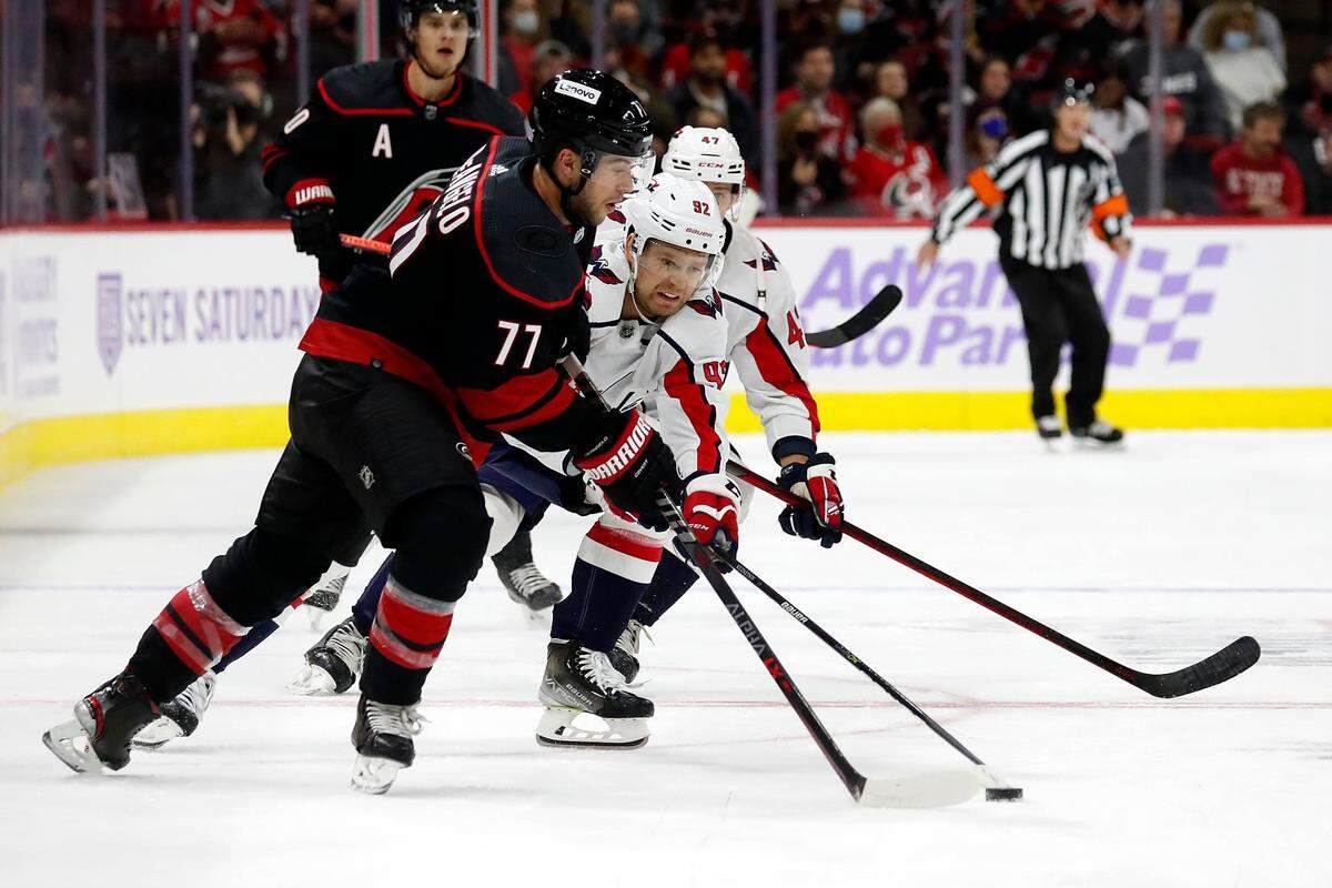 Washington Capitals’ Evgeny Kuznetsov (92) reaches for the puck controlled by Carolina Hurricanes’ Tony DeAngelo (77) during the first period of an NHL hockey game in Raleigh, N.C., Sunday, Nov. 28, 2021. (AP Photo/Karl B DeBlaker)